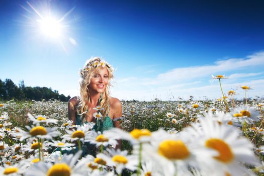 Beautiful girl in dress on the sunny daisy flowers field
