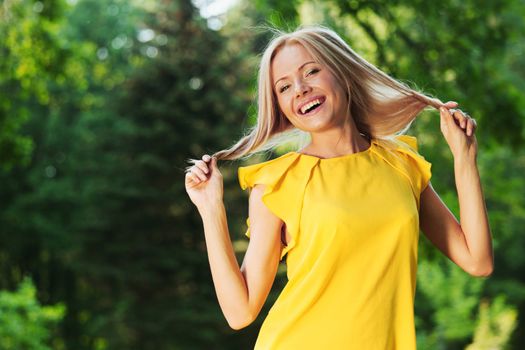 happy woman in yellow dress posing against a background of trees