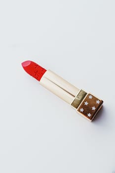 Luxury lipstick in a golden tube on white marble background, make-up and cosmetics concept