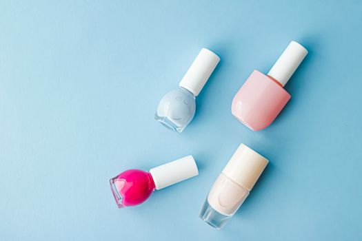 Colourful nail polish bottles on blue background, organic make-up and cosmetic products for beauty brand, close-up