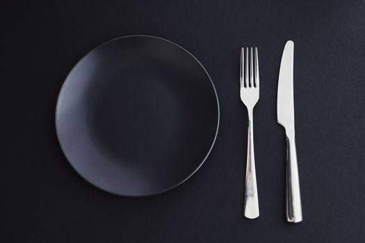 Empty plates and silverware on black background, premium tableware for holiday dinner, minimalistic design and diet concept