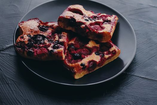 Berry pie on black plate, rustic homemade food with organic ingredients on black background