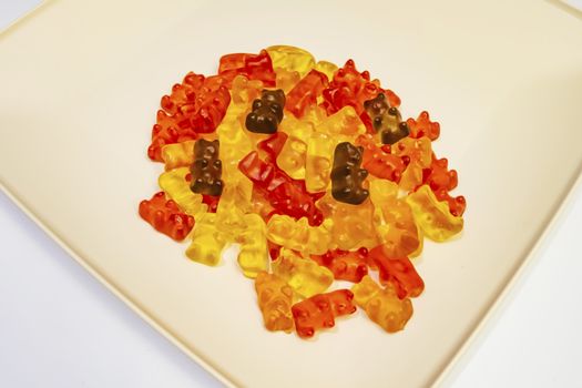 teddy bear figured and colorful jelly beans in plate on white background.
