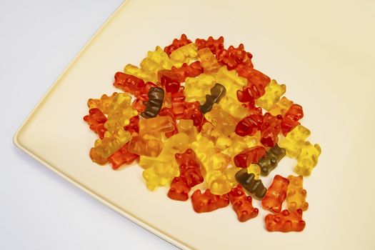 teddy bear figured and colorful jelly beans in plate on white background.