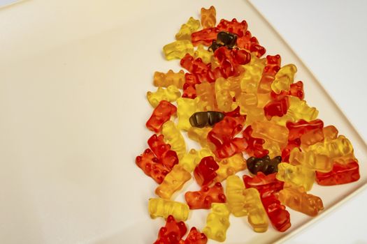 teddy bear figured and colorful jelly beans in plate on white background.