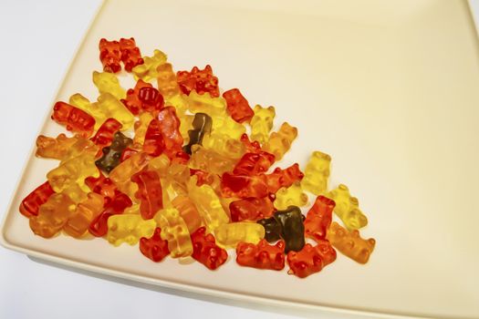 teddy bear figured and colorful jelly beans in plate on white background.