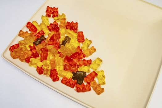 teddy bear figured and colorful jelly beans in plate on white background.