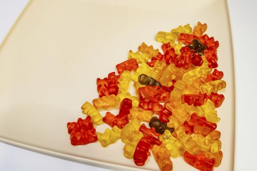 teddy bear figured and colorful jelly beans in plate on white background.