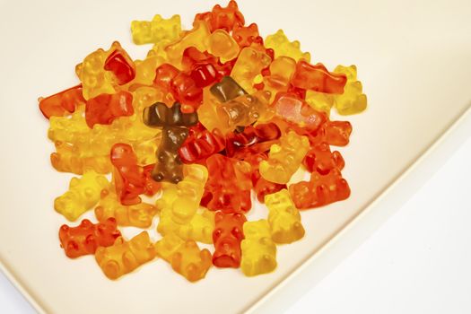 teddy bear figured and colorful jelly beans in plate on white background.