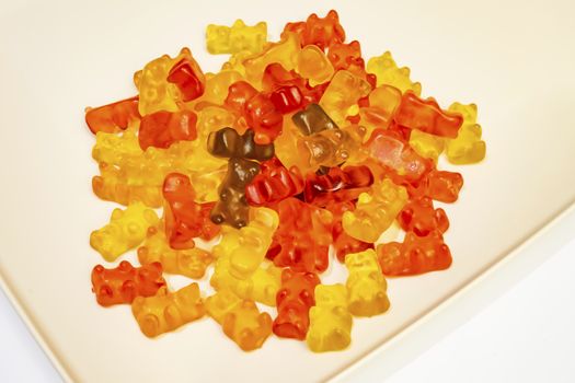 teddy bear figured and colorful jelly beans in plate on white background.