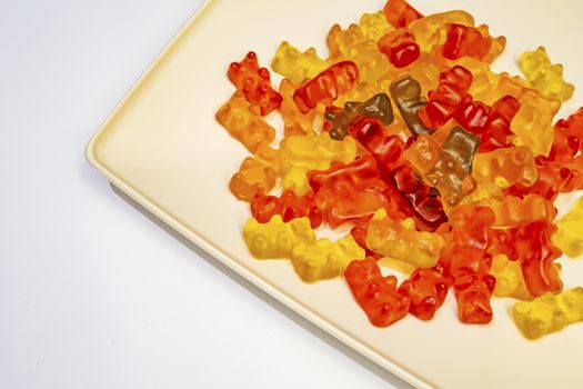 teddy bear figured and colorful jelly beans in plate on white background.