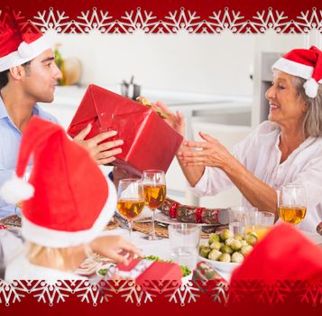 Composite image of family exchanging christmas presents against snowflake frame
