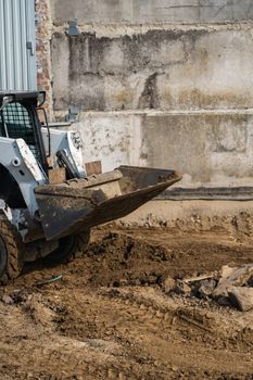 White skid steer loader at a construction site working with a soil. Industrial machinery. Industry