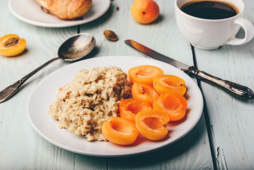 Breakfast set. Porridge with sliced apricot, cup of coffee, glass of grapefruit juice and croissant