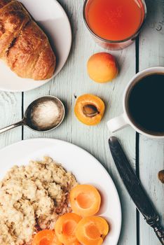 Breakfast set. Porridge with sliced apricot, cup of coffee, glass of grapefruit juice and croissant