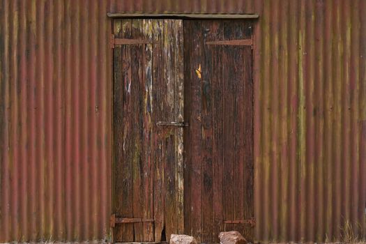 An old corrugated iron sheet toolshed with weathered wooden door, Rustenburg, South Africa