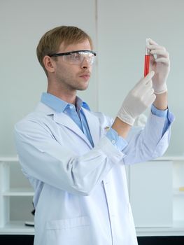 A young brazilian scientist with lab safety goggles is considering the color of chemicals to observe the acidity of the alkalinity.