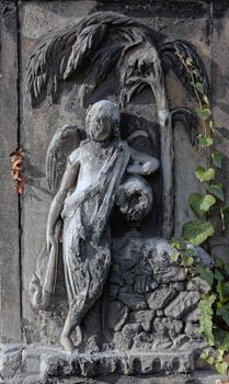 Eroded cemetery angel statue with palm tree