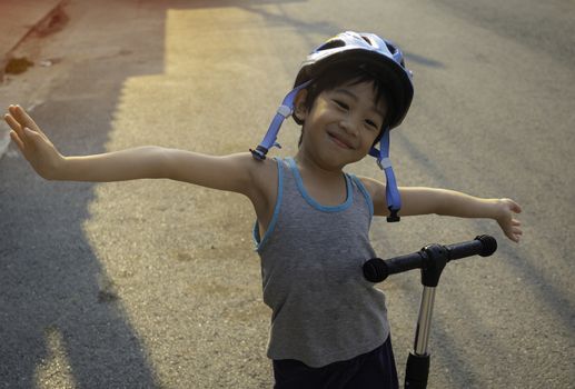 A 4-year-old Asian boy smiled happily with the opportunity to exercise by riding a scooter in the evening during the coronavirus crisis.