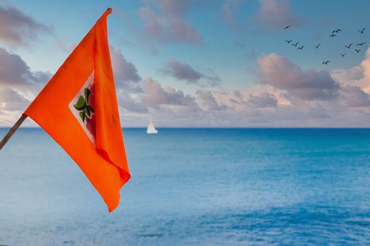 Orange Flag with Sea and White Sailboat in Background