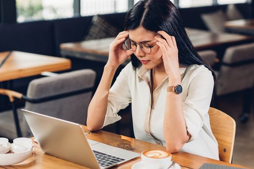 Lifestyle freelance working woman and laptop computer he headache unhappy on job in coffee cafe shop