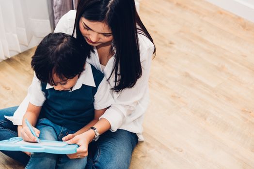 Child kid boy son kindergarten and beautiful mother teaching drawing together at interior room home