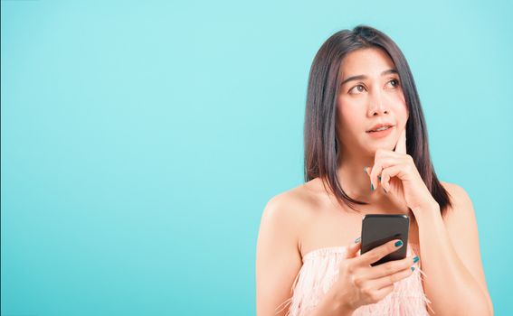 portrait asian beautiful woman her holding mobile phone her confused and thinking on blue background, with copy space for text