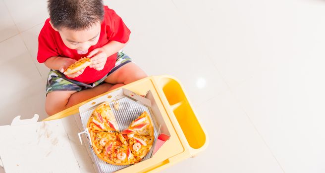 Hot Homemade, Vegetarian fast Italian food, Top view of Cute Little Child enjoying eating Delivery Pizza pepperoni, cheese many slices deliciously in a cardboard box at home with copy space for text