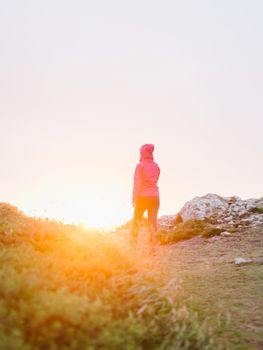 Woman walking away in the sunlight on a hill top footpath at Pembrokeshire Coast Path at sunset in Martin's Haven - Pembrokeshire, West Wales.