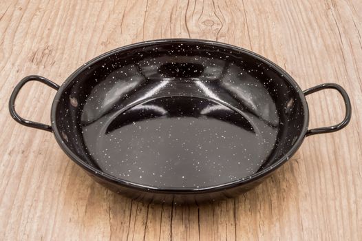 Empty paella pan on an old kitchen table, ready to cook