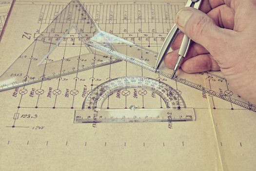 Electrical engineer workplace -  electrotechnical project, rulers,  and divider compass. Construction and electrotechnology concept. Engineering tools. Circuit diagram on background. Retro haze. Construction projects. Planning