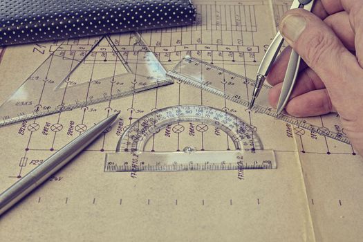 Electrical engineer workplace -  electrotechnical project, rulers,  and divider compass. Construction and electrotechnology concept. Engineering tools. Circuit diagram on background. Retro haze