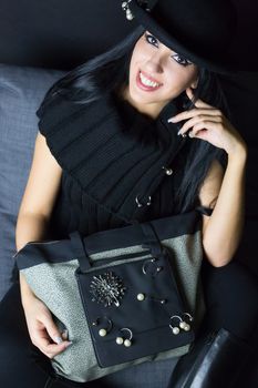 woman smilig on her sofa in fashion dress and bag