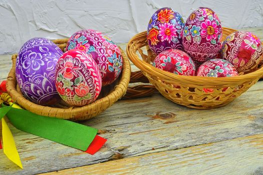 Still life with Easter eggs.  Decorated Easter eggs lay in a wicker basket on a white wooden background. Easter eggs, decorated with traditional folk designs - east Europe, Czech Republic