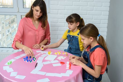 Mom and two daughters play board games