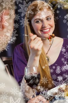 Pretty woman smiling at her husband during dinner against snowflakes on silver