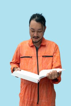 The chief mechanic in an orange uniform holding big book. Stand and read the maintenance manual carefully. Portrait with studio light.