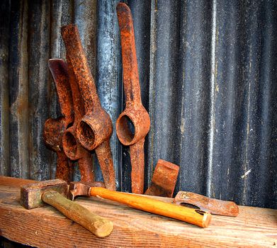 Rusty pick axe heads and a hammer in a tool shed