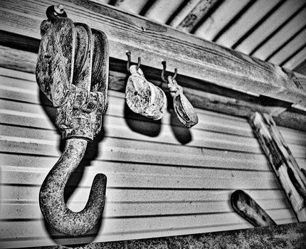 Rusty hooks and pulleys in a tin shed with noise in greyscale