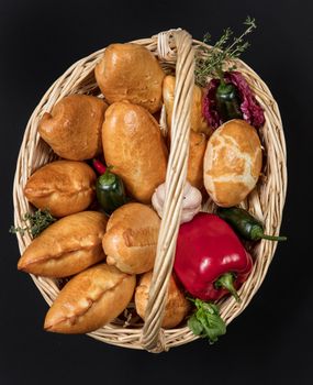 Pies with meat in the wicker basket on a black background