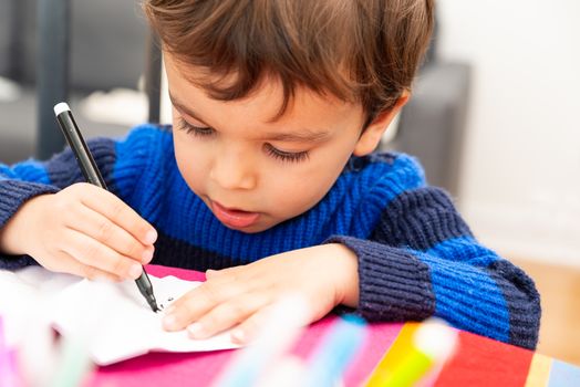 Toddler drawing at home with a black felt pen