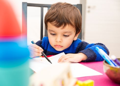 Toddler drawing at home with a black felt pen