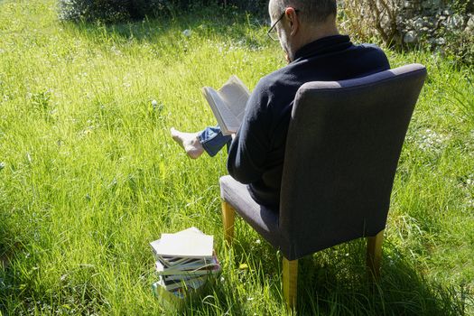 a man reads a book in the garden lawn during a coronavirus quarantine