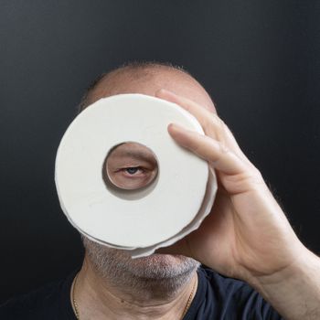 a man looks through a roll of toilet paper