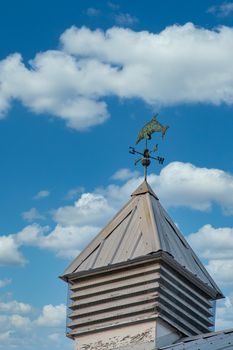 An old rustic cupola with a dolphin weather vane