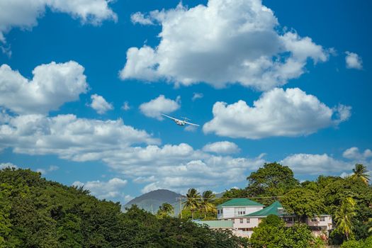 A twin propeller plane taking off over a tropical paradise