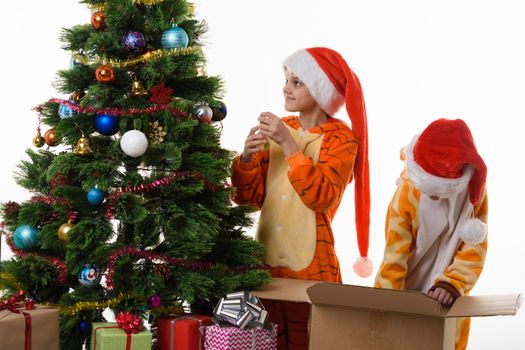 Girls decorate a Christmas tree, one of them delves into a box with toys