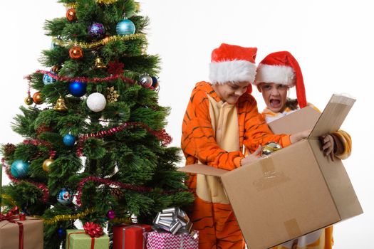 The girl funny holds a box with New Year's toys, another girl delves into a box