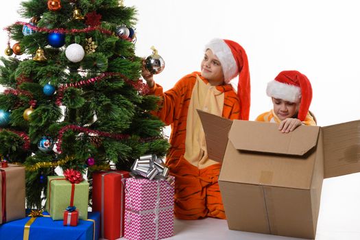 Dona girl takes the ball from the Christmas tree, the other puts the toys in the box