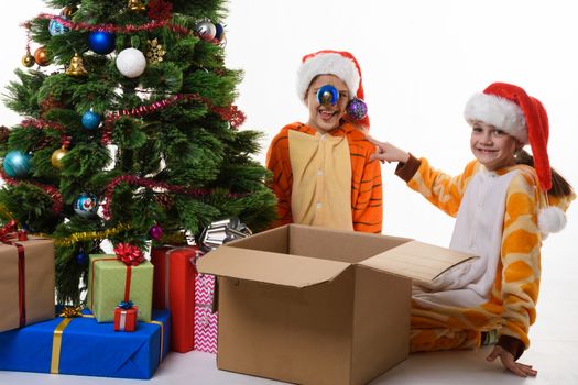 The girl hung Christmas balls on her sister's hat and looked into the frame with a smile